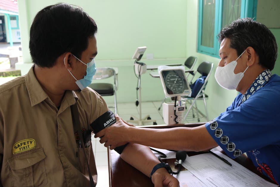 Healthcare professional measuring patient's blood pressure in a medical setting.