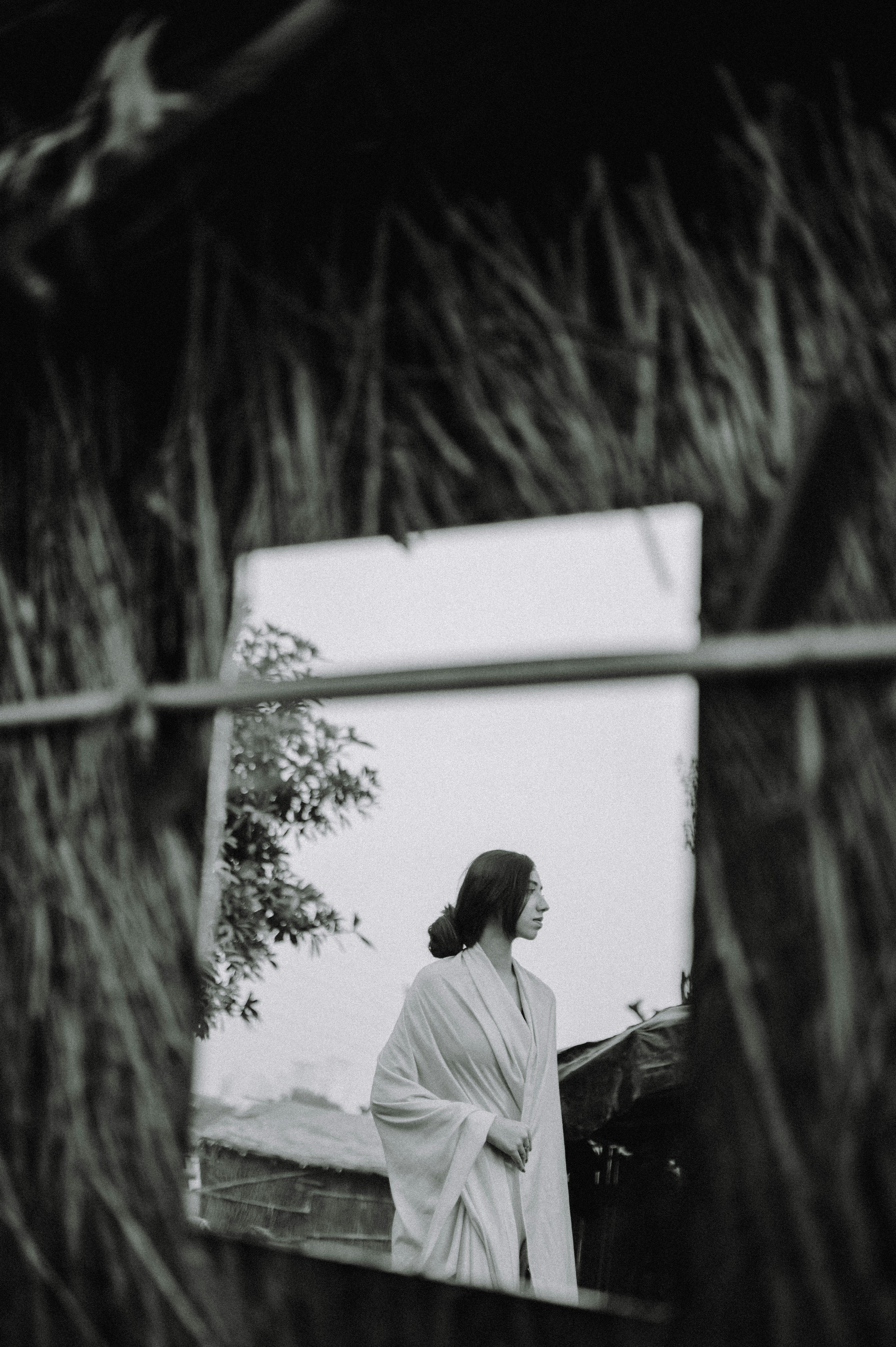Black and white portrait of a woman reflecting in a rustic setting, New Delhi.