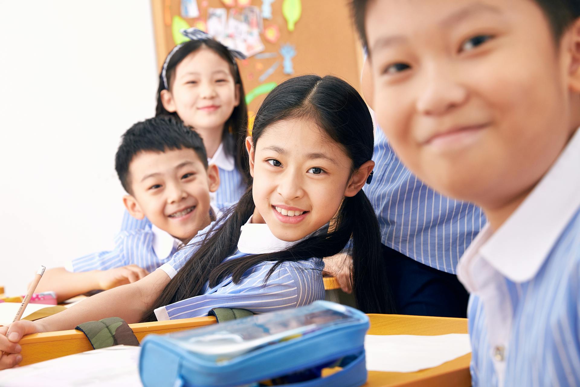 Happy schoolchildren in class wearing uniforms, engaging in studies and posing for a photo.