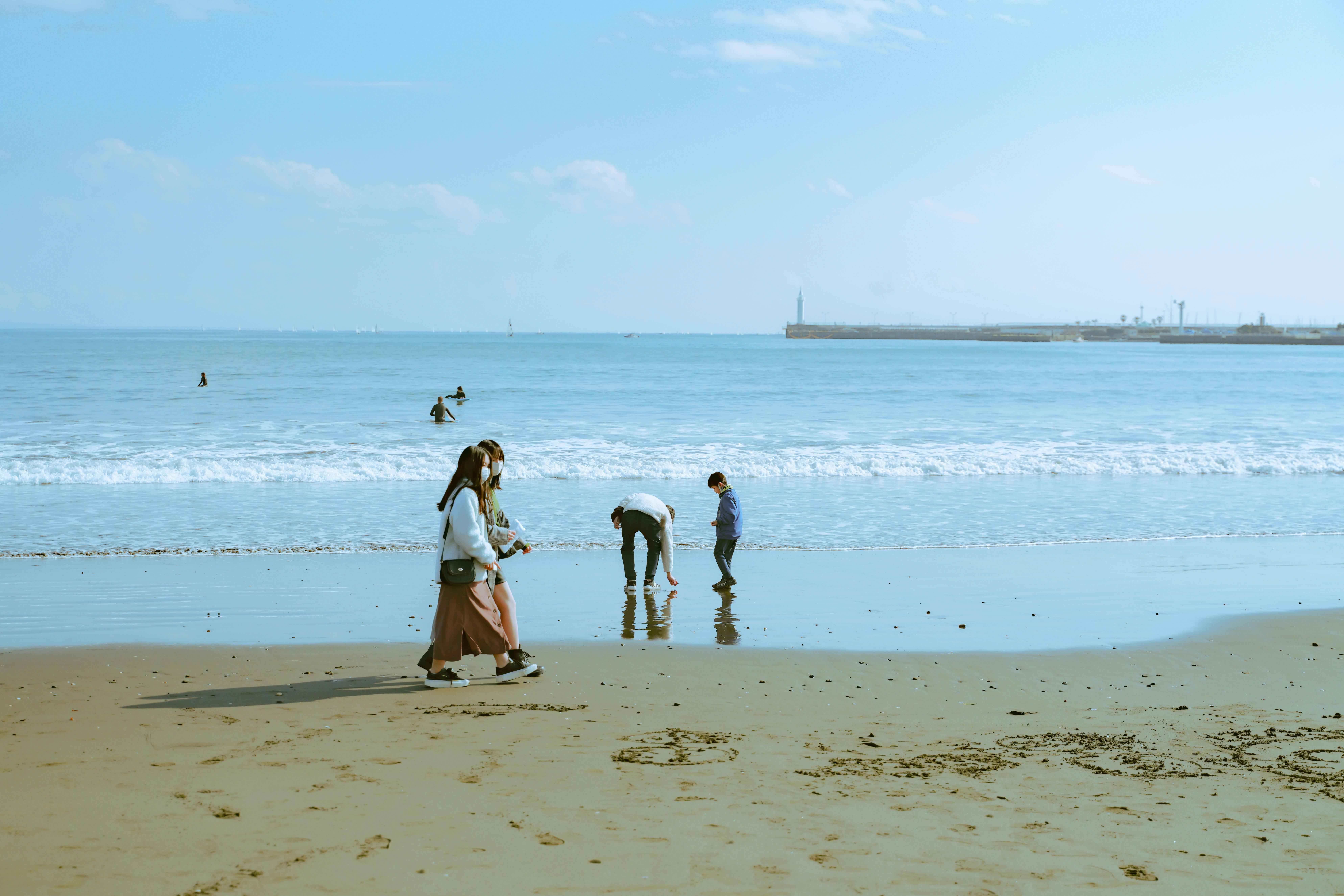 A family walks and plays by the sea on a sunny day, capturing modern outdoor leisure.