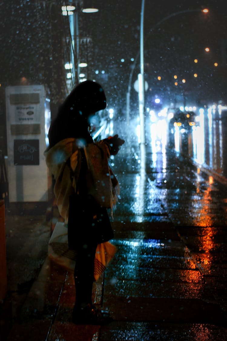 Woman Standing On The Side Of The Road While Snowing