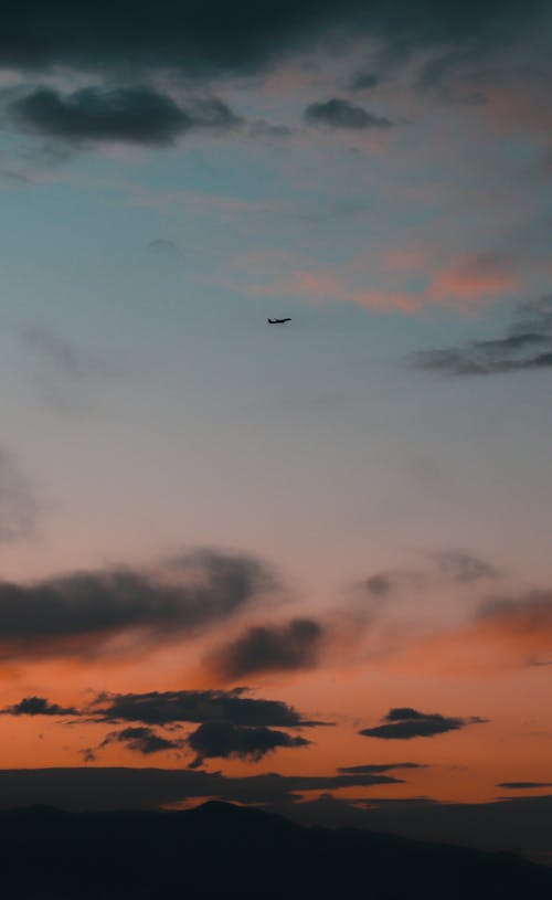 Airplane Flying over the Clouds during Sunset