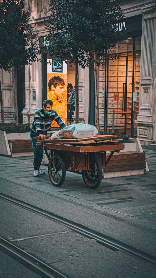 Man Pushing a Cart in City Streets