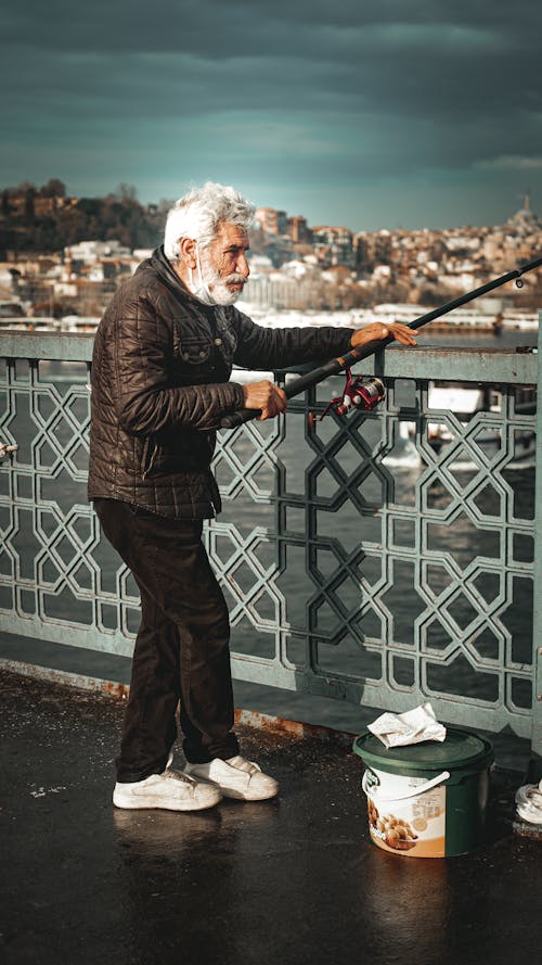 Elderly Man Fishing While on a Bridge