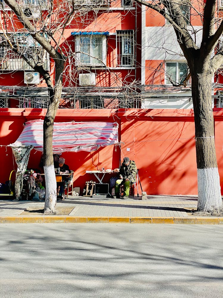 Traders On Street In Front Of Red Wall