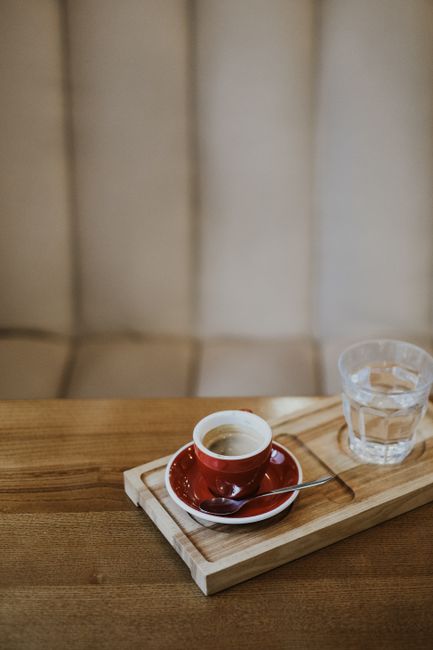 A cozy coffee setup with espresso cup and water on a wooden tray in a cafe.