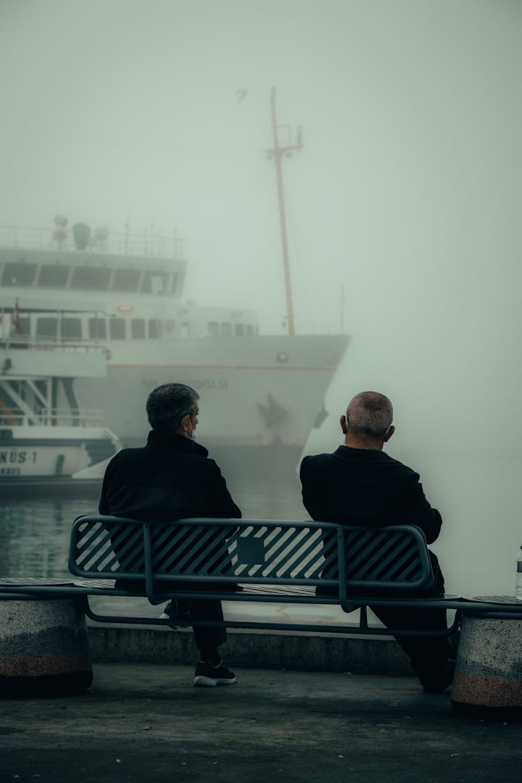 Back View Of Elderly Men Sitting On A Bench 