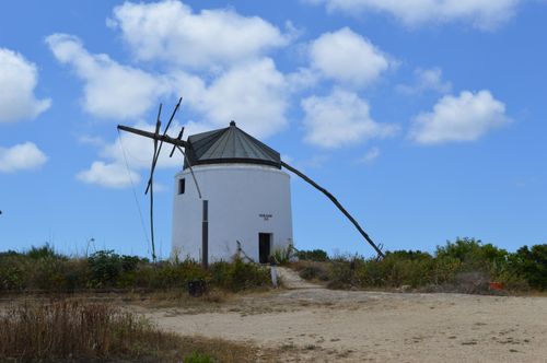 Free A picturesque windmill set against a bright blue sky and fluffy clouds. Stock Photo