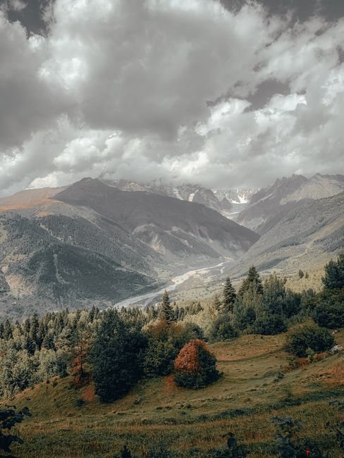 Breathtaking view of the lush Mestia mountains with dramatic clouds overhead.
