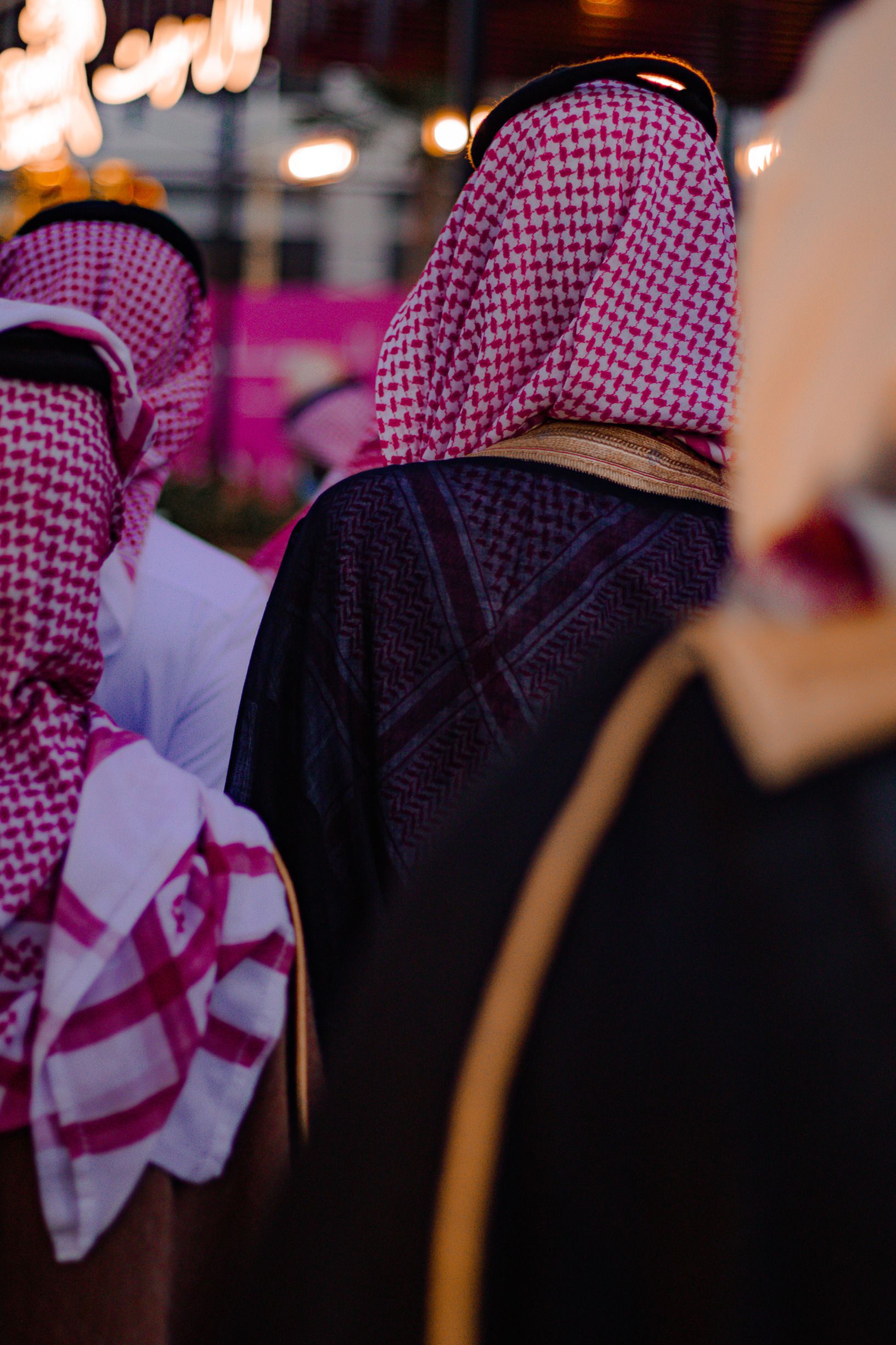 A group of men in traditional Saudi dress enjoying an outdoor gathering, showcasing cultural attire.