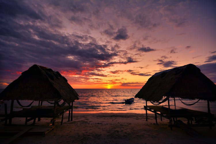 Scenic View Of Cabanas In The Beach During Sunset