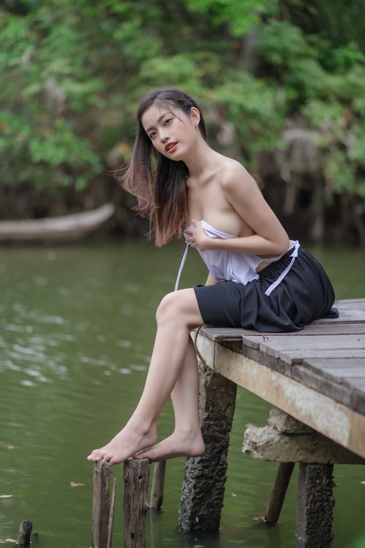 Surprised Girl Sitting On Pier And Covering Breasts