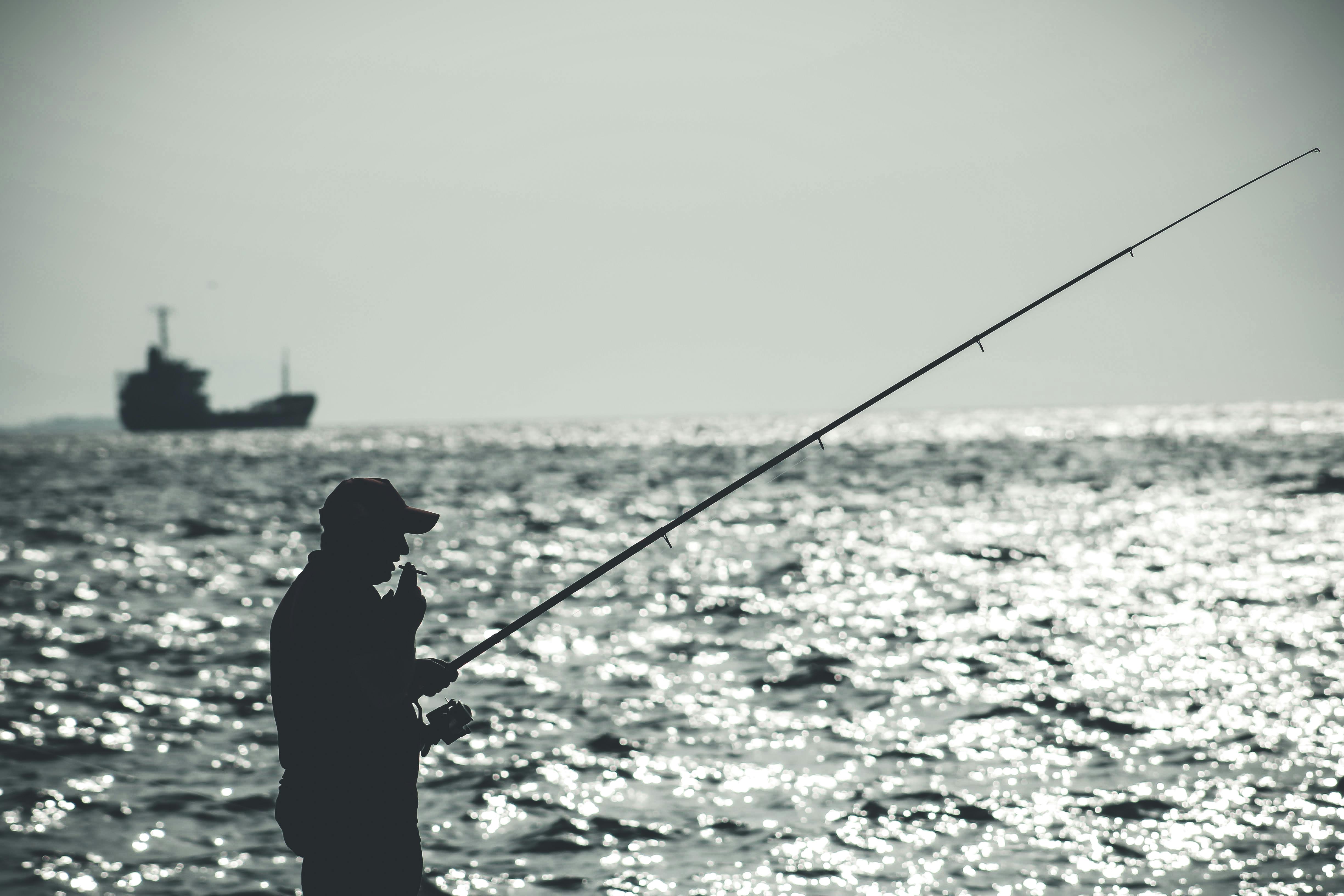 Grayscale Photography of Man Holding a Fishing Rod Near Body of Water · Free  Stock Photo