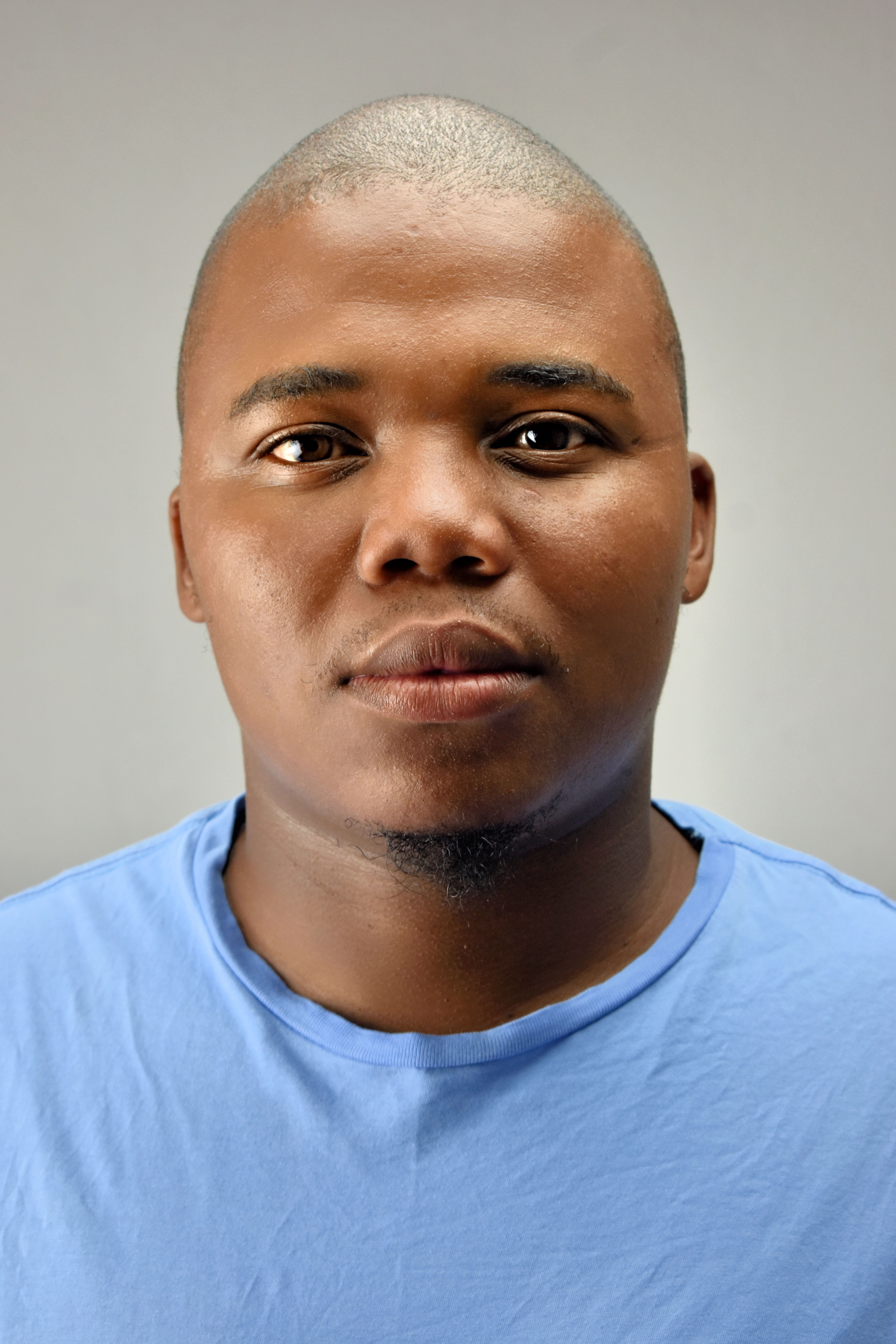 Close-up portrait of a man wearing a light blue shirt against a neutral background.