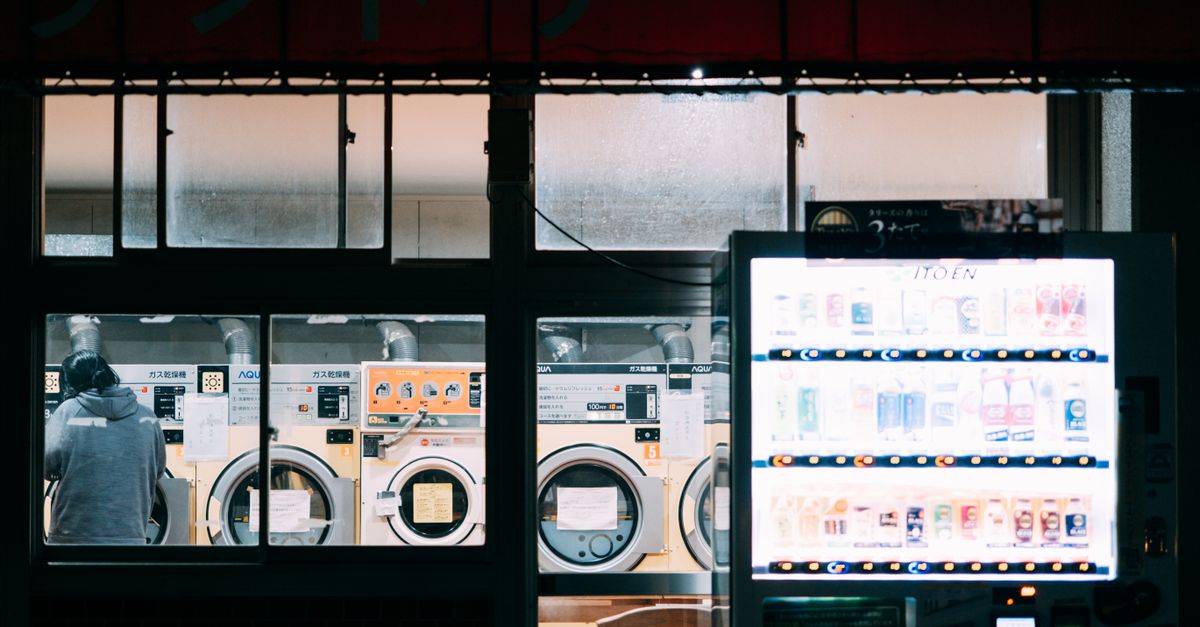 A cozy nighttime scene at a laundry shop with a bright vending machine and washing machines.