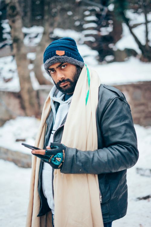 Free A man dressed warmly in a snowy setting, wearing a scarf, beanie, and jacket. Stock Photo