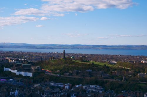 Free A stunning aerial view of Edinburgh featuring Calton Hill, the cityscape, and the Firth of Forth on a clear day. Stock Photo