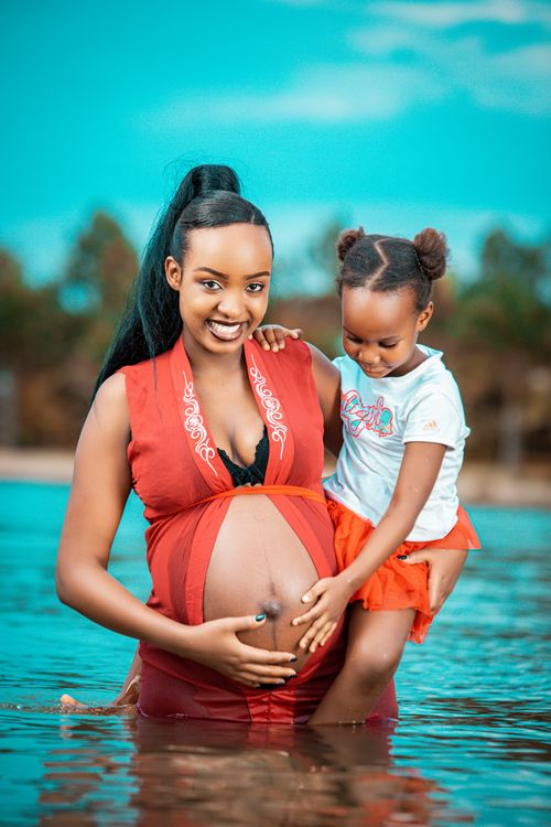 Free A pregnant woman and her daughter enjoying time together in the water outdoors. Stock Photo