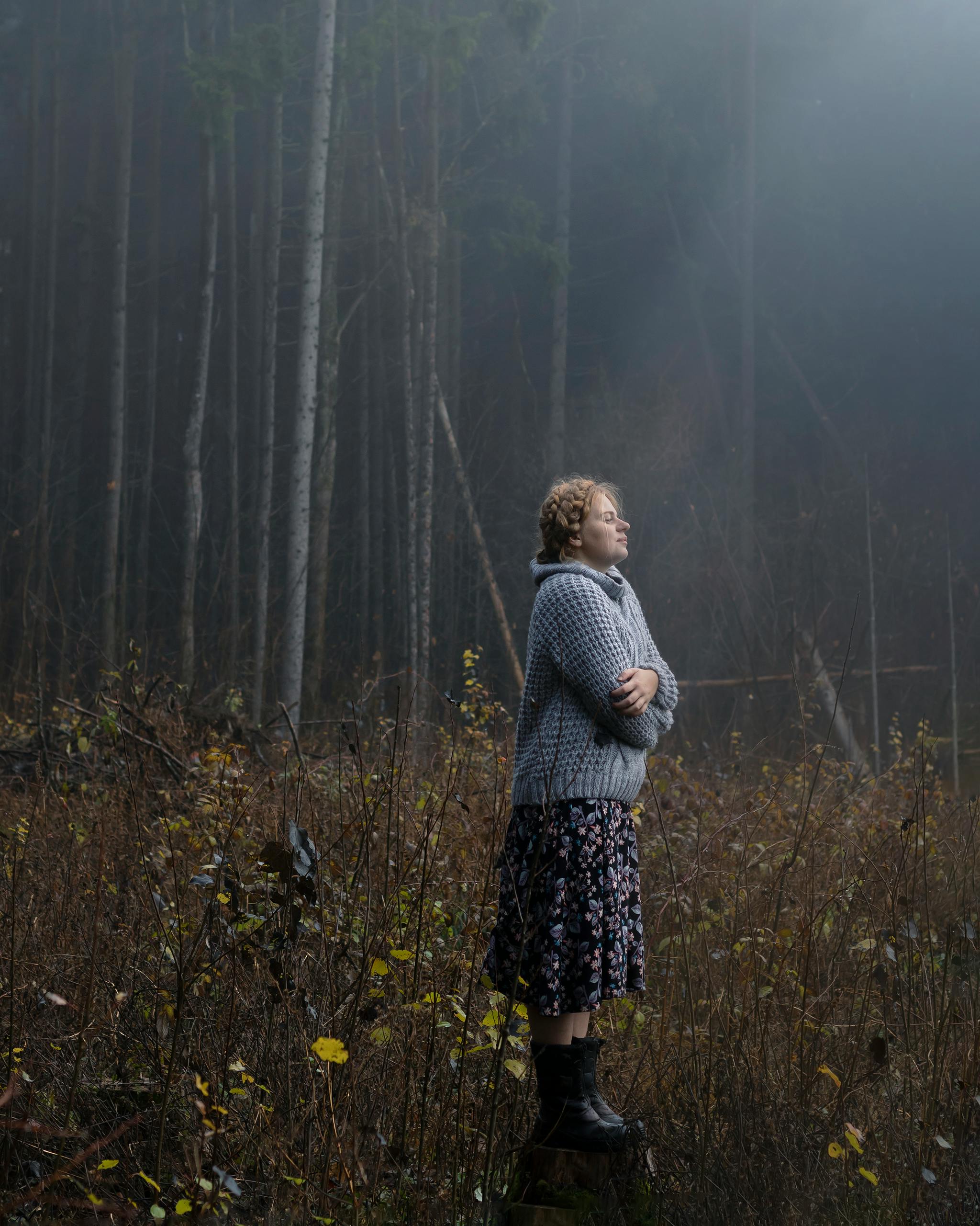 adult woman standing in forest clearing in light of morning sun