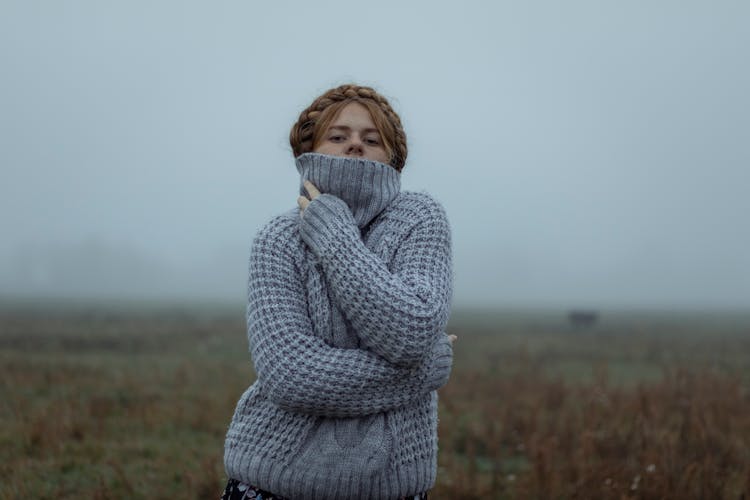 Young Redhead Woman In Gray Knitted Pullover Standing In Fields