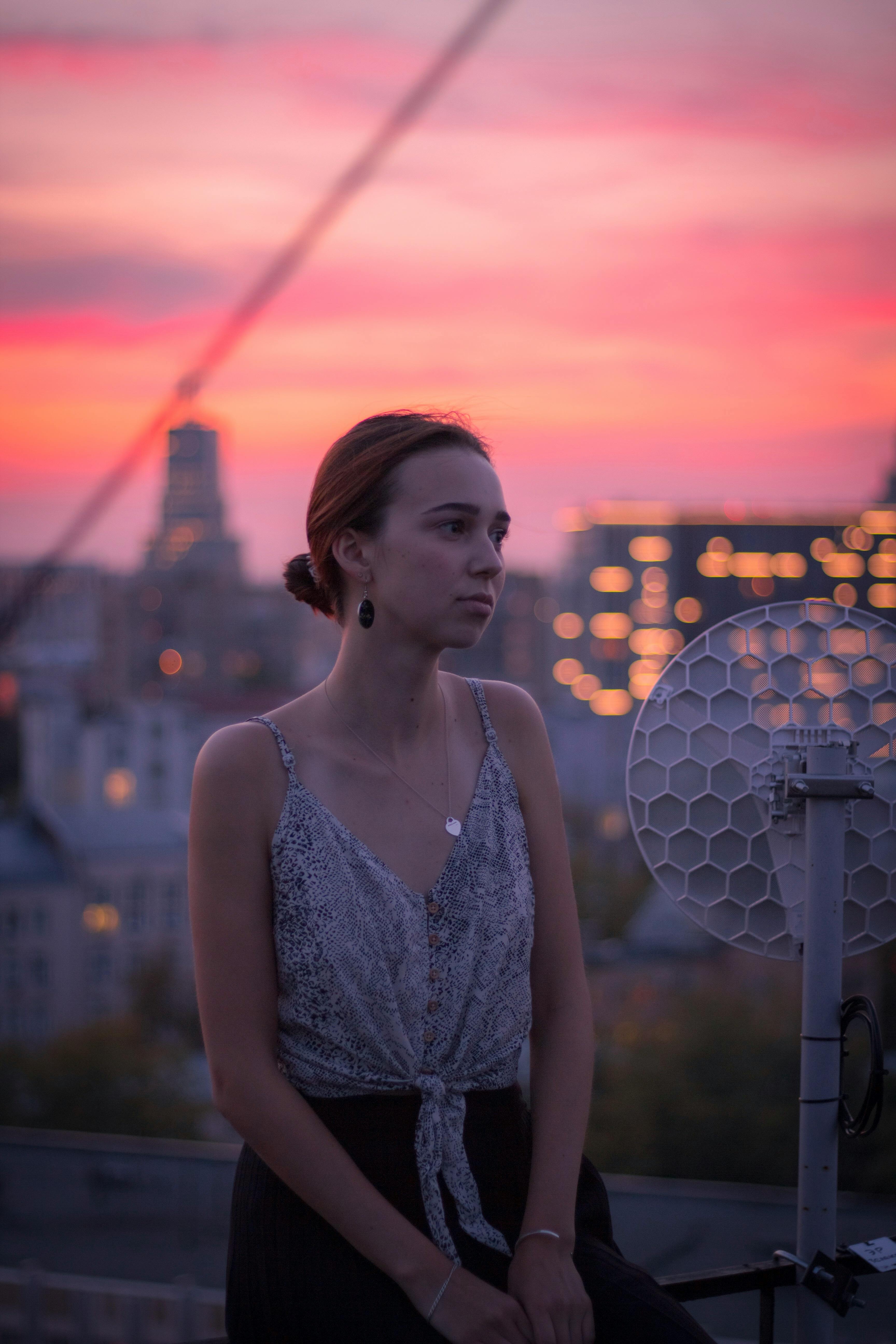 Caucasian woman in spaghetti strap top during colorful Moscow sunset. Urban backdrop.