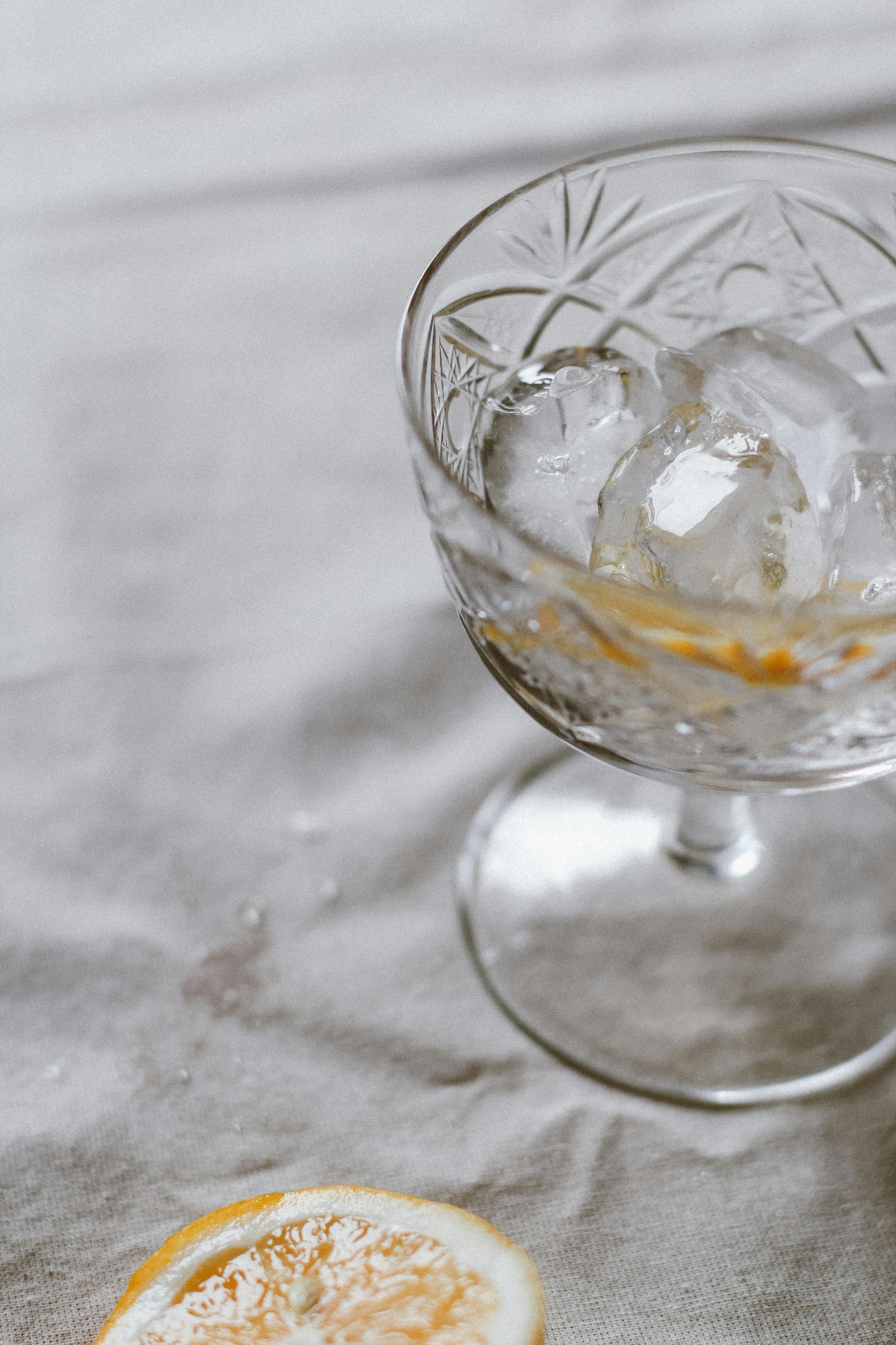 Close-up of an elegant crystal glass with ice cubes and a lemon slice, exuding freshness.