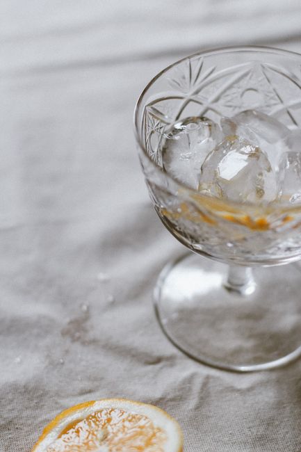 Close-up of an elegant crystal glass with ice cubes and a lemon slice, exuding freshness.