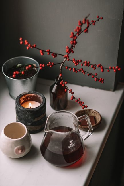 A warm and inviting home decor setup with candle light, tea, and a potted plant on a windowsill.