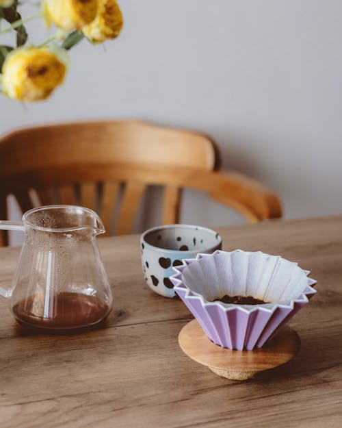 Free Clear Glass Pitcher Beside White and Black Polka Dot Ceramic Cup on Brown Wooden Table Stock Photo