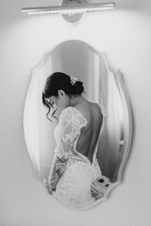 Mirror Reflection of Bride Putting on Wedding Dress
