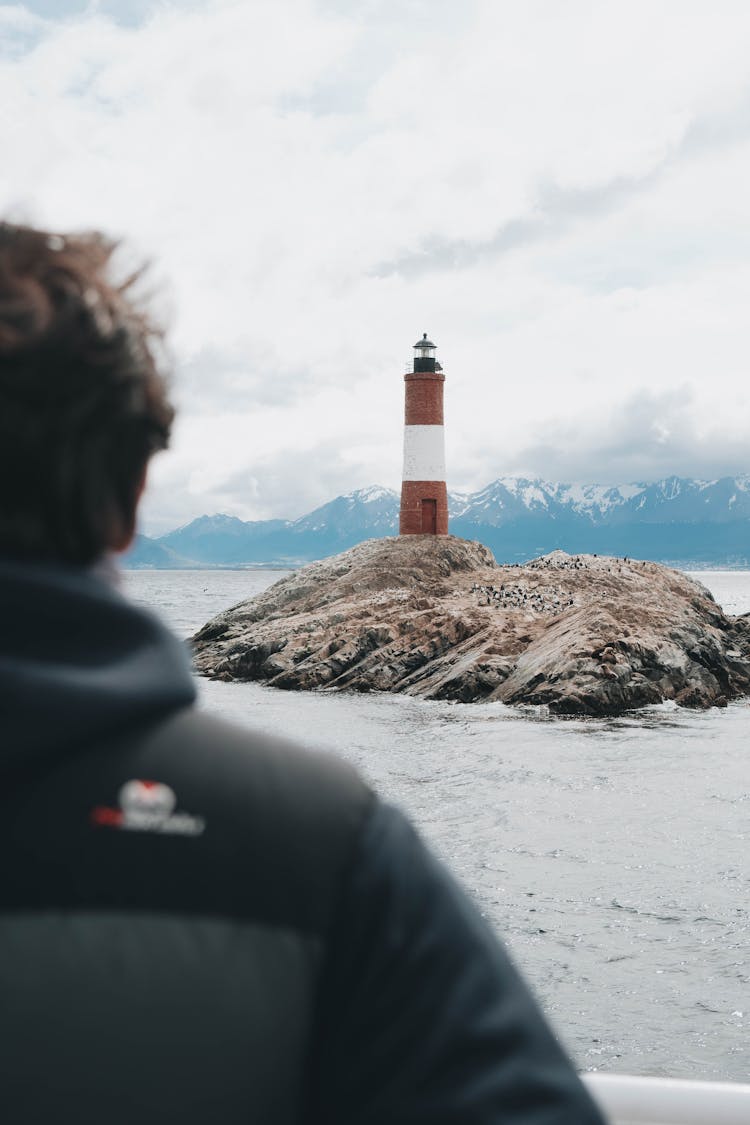 A Person In Winter Jacket Looking At The Lighthouse