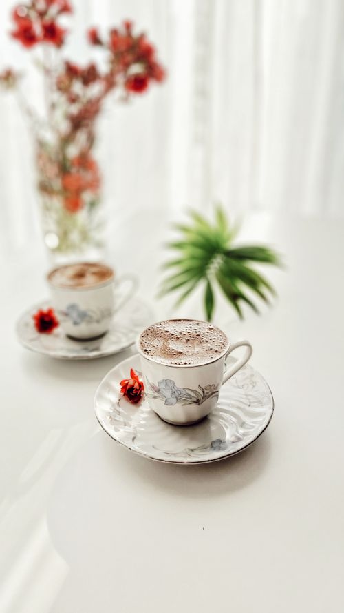 Free Stylish coffee cups with flowers on a table, perfect for morning relaxation. Stock Photo