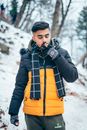 Man in Black Leather Jacket and Orange Pants Standing on Snow Covered Ground