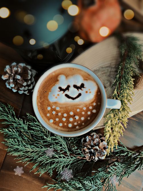 Free A warm cup of coffee with cute latte art, surrounded by pinecones and evergreen branches, evoking a cozy winter feel. Stock Photo