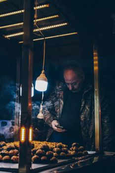 Street vendor selling roasted chestnuts under warm lights in Istanbul at night.