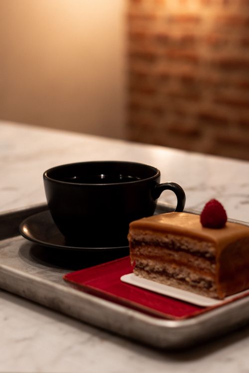 Free Delicious chocolate layer cake with a raspberry, served with coffee on a marble table. Stock Photo