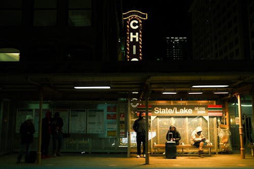 People Waiting on an Illuminated Strain Station at Night