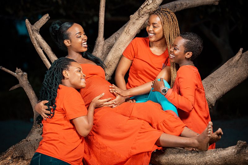 An expectant mother smiling, surrounded by her family outdoors