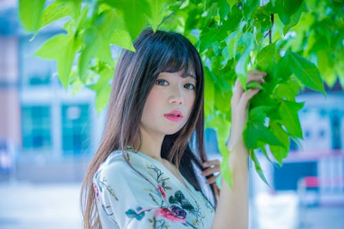 Woman Wearing White and Pink Floral Shirt Holding Leaf