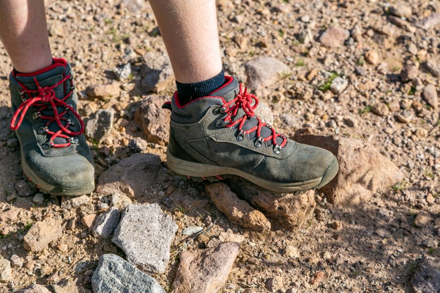 Green trail shoes with red laces on a rocky path