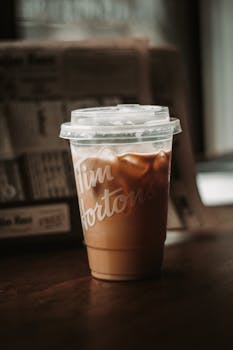 Close-up of iced coffee in a disposable cup on a table indoors. Perfect for refreshing beverage themes.