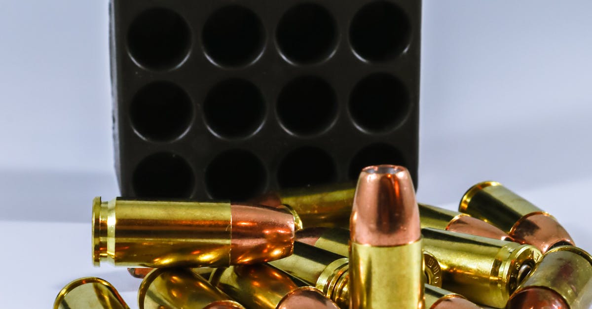 Close-up of brass bullets and a black ammunition case on a white surface, showcasing firearm components.