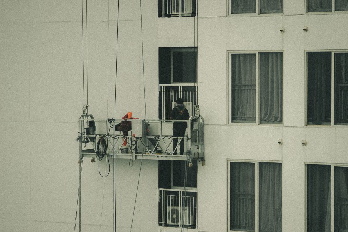 Service workers in safety gear on a building facade, in the field and away from the phone when calls come in