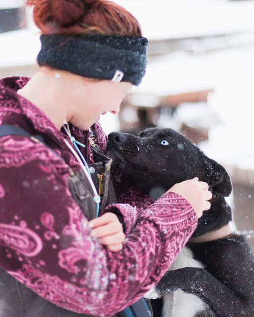 Free A woman in a winter jacket lovingly embraces a black and white husky dog in a snowy outdoor setting. Stock Photo
