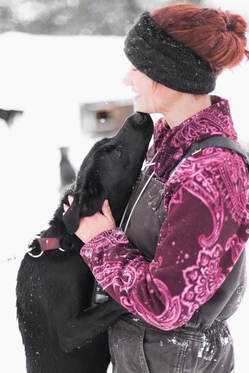 Free A woman embraces her black Labrador dog outdoors in a snowy winter scene, showcasing affection and companionship. Stock Photo