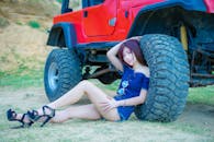 在台北市，一名年轻女子站在一辆红色吉普车旁摆姿势