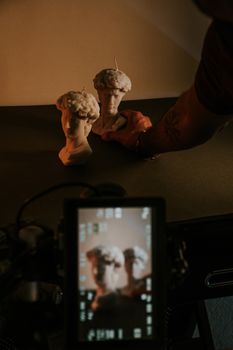 Two sculpture candles being arranged on a table, captured artistically.