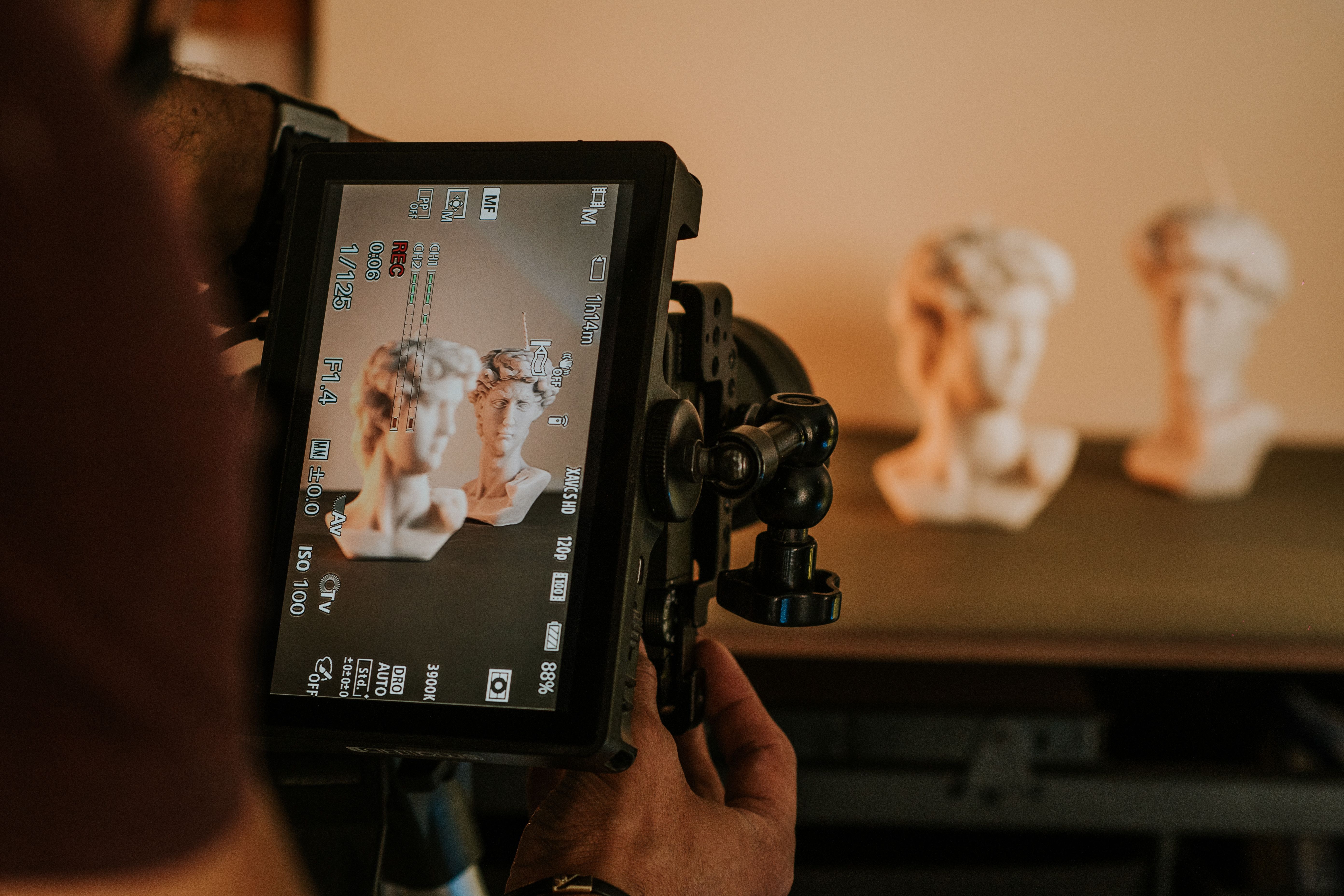 Photographer using camera to capture sculptures in studio setting with focus on digital screen.