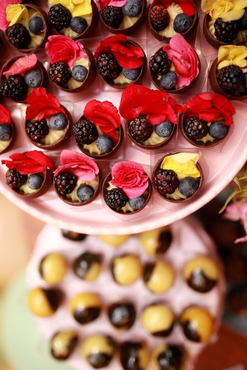 Free Close-up of delicious berry desserts topped with vibrant edible flowers on a pink stand. Stock Photo