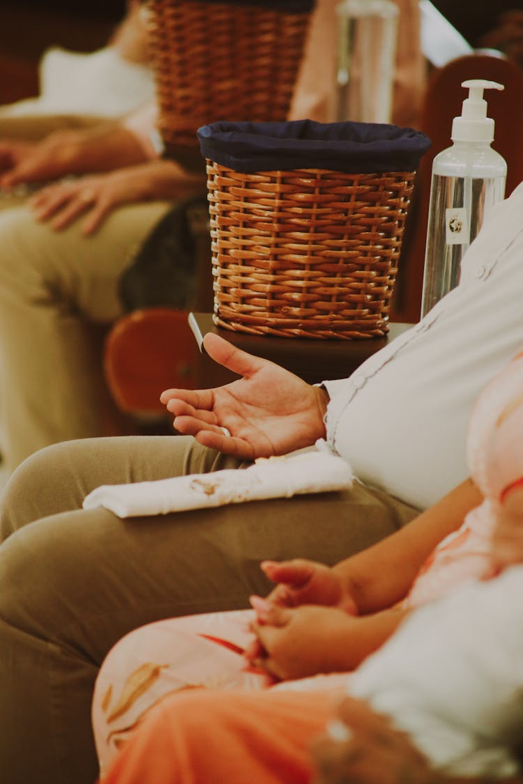 Close-up Of People Sitting In A Row With Baskets Between Them 